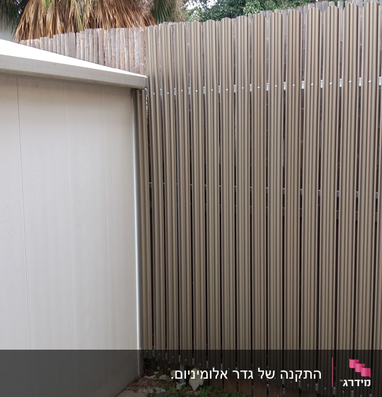 גדר עץ גבוהה ליד קיר מתכת אפור